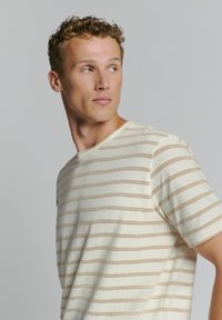 Gestreiftes Strick-T-Shirt in Creme und Beige mit kurzen Ärmeln, rundem Ausschnitt und offenem Gewebemuster.