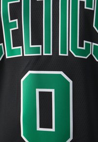 La maglia da basket nera presenta la scritta "CELTICS" in verde con contorni bianchi, include un grande numero "0" in verde sotto. La texture in rete è visibile.