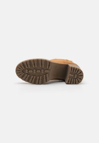 Stivale in suede marrone con suola in gomma spessa, caratterizzato da un battistrada scanalato per una migliore aderenza e un design imbottito per il massimo comfort.