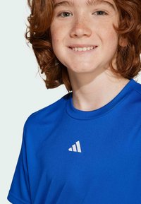 Blaues Sport-T-Shirt aus glattem Stoff mit Rundhalsausschnitt und einem weißen dreieckigen Logo auf der Brust. Kurze Ärmel, leichtes Design.