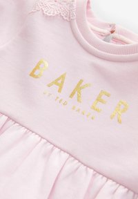 Różowa bawełniana sukienka z złotym logo "BAKER", koronkowymi detalami na ramionach oraz marszczoną spódnicą. Zapięcie na guziki z tyłu.