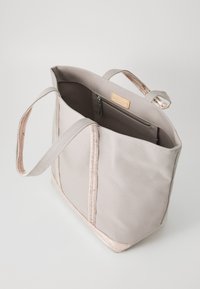 Taška cez plece v svetlošedej plátne s ružovo zlatými akcentmi, s dvoma držadlami a vnútornou zipsovou kapsou na bezpečné uloženie.