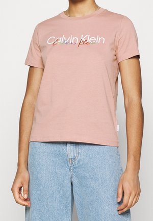 Jasnoróżowa bawełniana koszulka z krótkim rękawem i okrągłym dekoltem. Na piersi znajduje się wielokolorowe haftowane logo. Luźny krój.