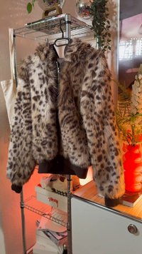 Blouson aviateur en fausse fourrure marron à pois noirs, avec fermeture éclair devant, poignets côtelés et coupe courte.