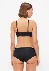 Black bra with textured lace and adjustable straps, paired with high-waisted, solid black brief. Notable hardware includes a clasp closure.