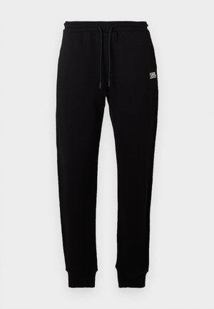 Pantaloni tuta neri in cotone con vita elastica e cordoncino regolabile. Piccolo logo bianco stampato sul davanti. Caviglie con polsini a coste.