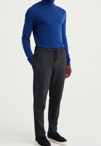 Blå polotröja och mörkgrå strukturerade joggers med elastisk midja och sidofickor. Kompletteras med mörka sneakers.