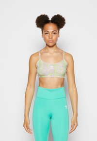 Sutiã em padrão de cobra verde claro e roxo com alças finas. Combinado com leggings turquesa de cintura alta. Textura suave, design atlético.