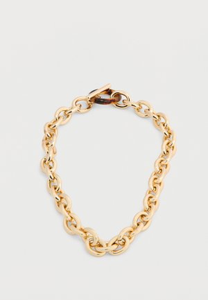 Χρυστό βραχιόλι με χοντρή αλυσίδα και κούμπωμα τύπου τορτοϊσέλ σε γκρι φόντο.