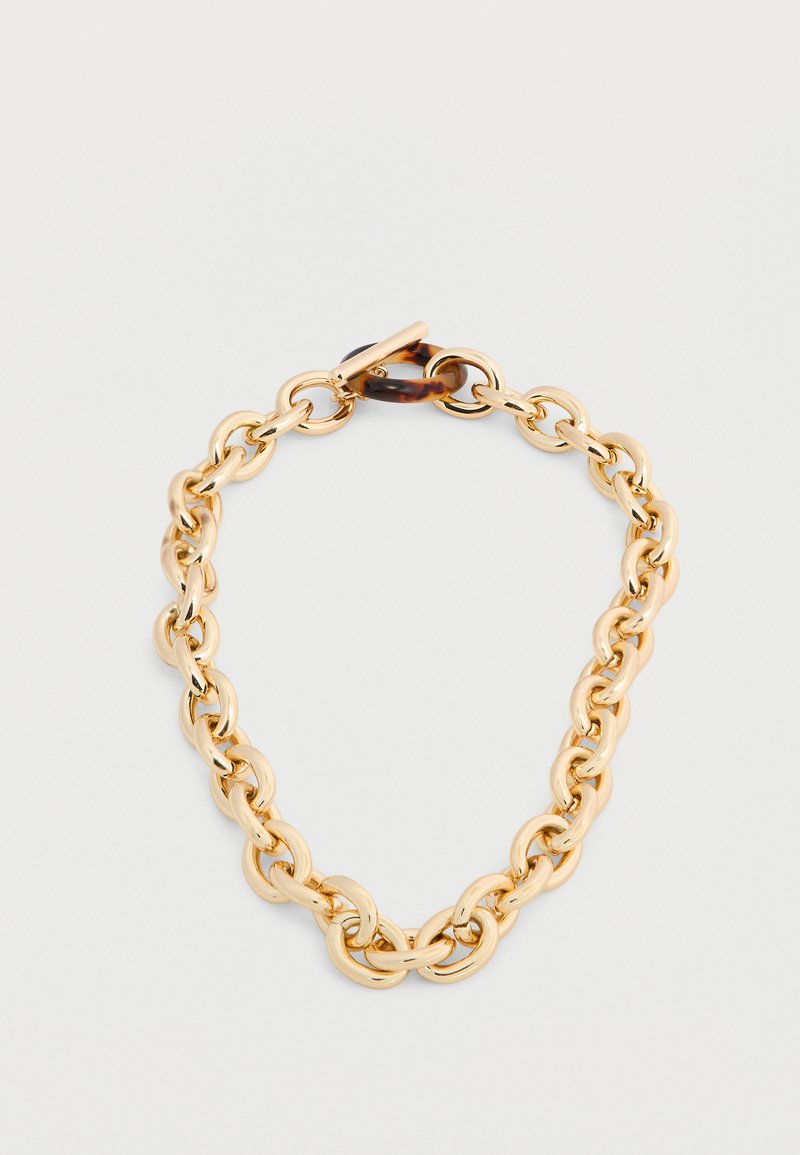 Χρυστό βραχιόλι με χοντρή αλυσίδα και κούμπωμα τύπου τορτοϊσέλ σε γκρι φόντο.