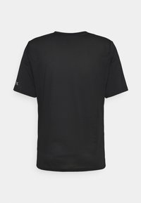 T-shirt de sport noir à manches courtes avec panneau arrière texturé et petit logo sur la manche gauche, vu de dos sur fond blanc.