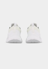 Ζευγάρι λευκά αθλητικά παπούτσια, φωτογραφημένα από πίσω, με ανάγλυφες σόλες και θηλιές για τράβηγμα, σε απλό λευκό φόντο.