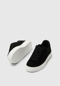 Sneakers in suede nero con suola in gomma bianca, dotati di allacciatura frontale, punta arrotondata e dettagli testurizzati sui lati.