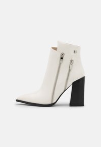 Stivaletto bianco in pelle con punta affilata, doppi zip laterali e tacco quadra nero. Texture liscia con un design moderno.