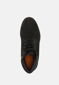 Bota de cuero negra con punta redonda, cuello acolchado y diseño de cordones. Presenta un forro interior marrón y suela cosida.