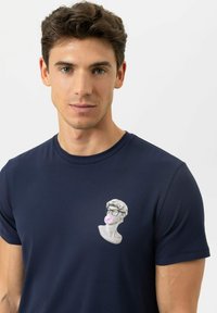Navyblauw T-shirt met een afbeelding van een marmeren buste met bril en roze kauwgom op de borst, gemaakt van een zachte katoenmix.