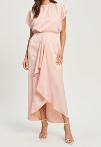 Light pink, satin maxi dress with cap sleeves, gathered waist, and draped front. Features an asymmetrical hem and delicate sandals.