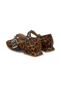 Zapatos planos de estampado de leopardo que presentan un material texturizado, una tira cruzada negra con tachuelas y un tacón bajo y anguloso.