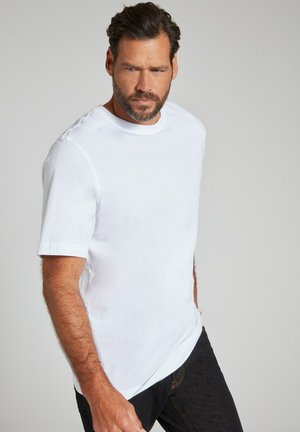 Hvid kortærmet T-shirt lavet af blødt stof, med en rund hals og sideslidser, parret med mørke jeans. Glat tekstur, klassisk pasform.