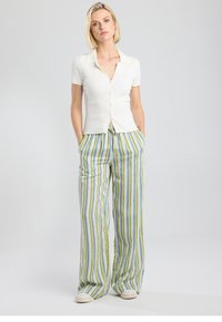 White ribbed short-sleeve button-up top paired with loose, multicolored striped pants in green, blue, and white. Casual fit with pockets.