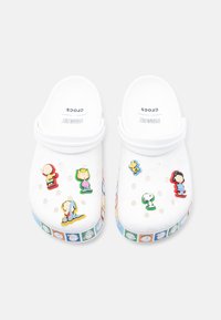 Λευκά Crocs με μπρελόκ χαρακτήρων Peanuts και πολύχρωμη λωρίδα με χαρακτήρες Peanuts γύρω από την σόλα.