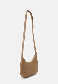 Borsa a spalla in pelle marrone con forma curva, singolo manico regolabile, chiusura con zip nella parte superiore e logo discreto sulla parte anteriore.