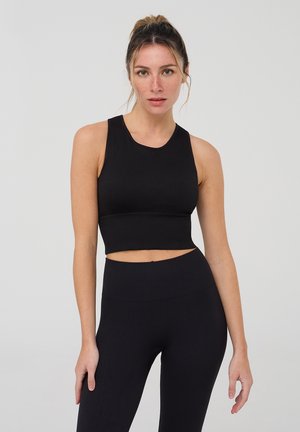 Top corto nero con scollatura rotonda e texture a coste, abbinato a leggings neri a vita alta, entrambi realizzati in tessuto elasticizzato.