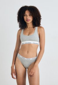 Szürke pamut melltartó és tanga, fehér pánttal, a "Calvin Klein" logóval. Sima textúrájú és minimalista dizájn.