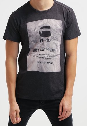 Lyhythihainen musta t-paita, jossa etupuolella on graafinen painatus tekstillä "G STAR RAW" ja "JUST THE PRODUCT". 100 % puuvillaa.