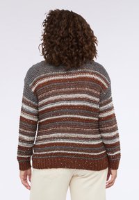 Texturovaný pletený svetr v přírodních tónech hnědé, šedé a krémové s horizontálními pruhy a volným střihem. Má žebrovaný lem a manžety.