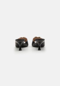 Black leather mules with a rounded toe, featuring a low, flared heel and gold accent details on the upper. Smooth texture and streamlined design.