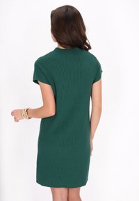 Korte groene geribbelde jurk met korte mouwen, voorzien van een hoge hals en een rechte snit. Glad textuur en een ontwerp tot op de knie.
