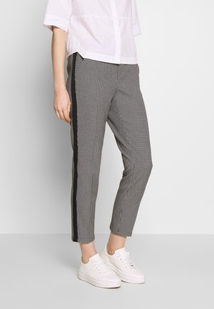 Rute-sorte og hvide bukser med sorte sidestriber, skræddersyet pasform, opkrøllede ankler, parret med hvide sneakers og en cropped hvid skjorte.