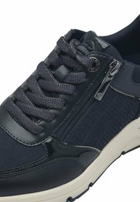 Sneaker blu navy con un mix di tessuto testurizzato e pelle lucida. Presenta una punta rotonda, lacci spessi, una chiusura con zip e una suola leggera.