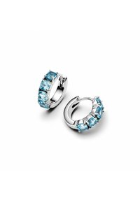 Huggie uhane v srebrni barvi z ovalnimi svetlo modrimi dragimi kamni, postavljenimi v ukrivljenem sprednjem delu, ki ponujajo poliran zaključek in šest skupin dragih kamnov.