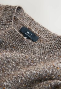 Brauner gestrickter Pullover mit strukturiertem Muster, ausgestattet mit einem gerippten Kragen und Bündchen. Etikett zeigt "NEXT, Regular Fit, M."