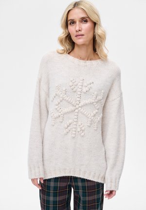 Jasnobeżowy sweter z teksturowanym wzorem płatka śniegu na środku. Charakteryzuje się luźnym krojem, ściągaczami na mankietach oraz szerokim dekoltem.