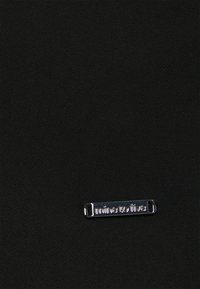 Tessuto nero texturizzato con un'etichetta rettangolare in argento metallico che riporta la scritta "mine to five" apposta sulla superficie. Design semplice e moderno.