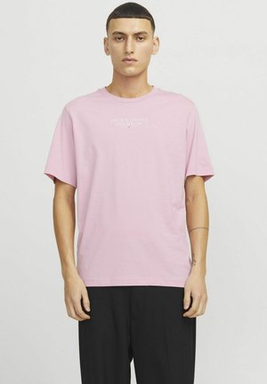Camiseta de algodón rosa claro con mangas cortas y cuello redondo, que presenta el texto blanco "JACK & JONES PREMIUM" impreso en la parte delantera.