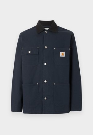 Σκούρο μπλε ναυτικό μπουφάν εργασίας με μαύρο γιακά, τέσσερις τσέπες μπροστά, μεταλλικά κουμπιά με τριπλό κούμπωμα και μικρό έμπλαστρο με το λογότυπο Carhartt στην επάνω δεξιά τσέπη.