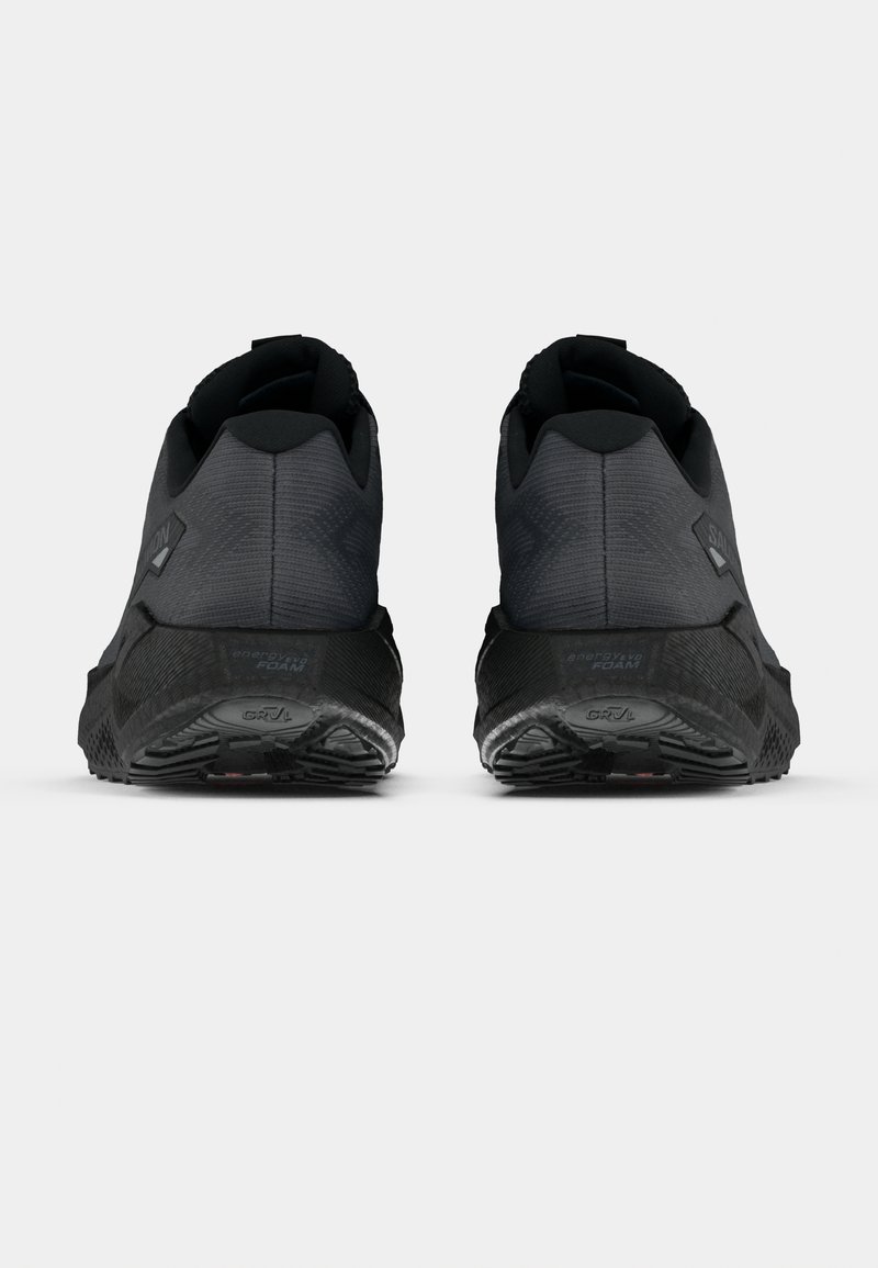 Un paio di scarpe da ginnastica nere viste da dietro, con suole testurizzate e colli imbottiti alle caviglie su uno sfondo bianco.