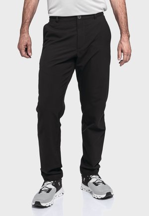 Schwarze Hosen aus glattem Stoff, mit Knopfverschluss und Taschen, kombiniert mit grau-schwarzen Sportschuhen.
