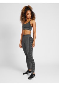 Grå sportig outfit med en åtsittande sport-bh och högmidjade leggings med texturerad detaljering och chevronmönstrade sidopaneler.
