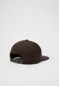 Cappello marrone con una forma strutturata, dotato di un visiera curva, chiusura snapback regolabile e tessuto testurizzato. Dettagli di cuciture rinforzate.