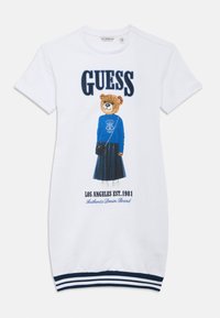 Λευκό φόρεμα με κοντά μανίκια που απεικονίζει έναν αρκούδο με μπλε πουλόβερ και κείμενο. Μανσέτες με ναυτικό ριγέ σχέδιο και μήκος μέχρι το γόνατο.