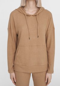 Felpa marrone a coste con cappuccio, cordini, tasca frontale e vestibilità morbida. Tessuto morbido e maniche lunghe, abbinata a pantaloni coordinati.
