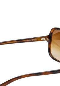 Ochelari de soare din tortoise cu lentile maro gradient, rame pătrate și accente metalice pe balama. Marcati "CONIC TORTOISE" pe braț.