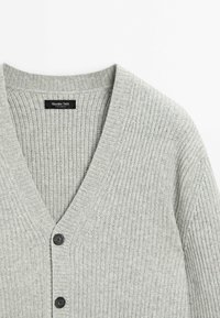 Cardigan en tricot gris clair côtelé avec col en V, deux boutons noirs et une étiquette noire "Massimo Dutti" à l'intérieur du col.