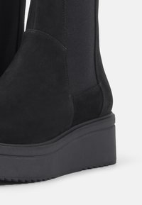 Černé kotníkové boty vyrobené z nubuku s elastickými bočními panely, silnou platformou a texturovanou podrážkou pro lepší přilnavost.