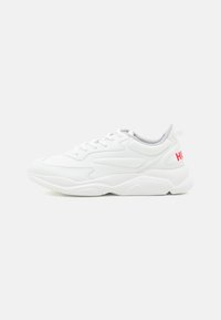 White athletic shoe with textured upper, lace-up design, padded collar, and a pink "HUGO" logo on the heel. Cushioned sole for comfort.